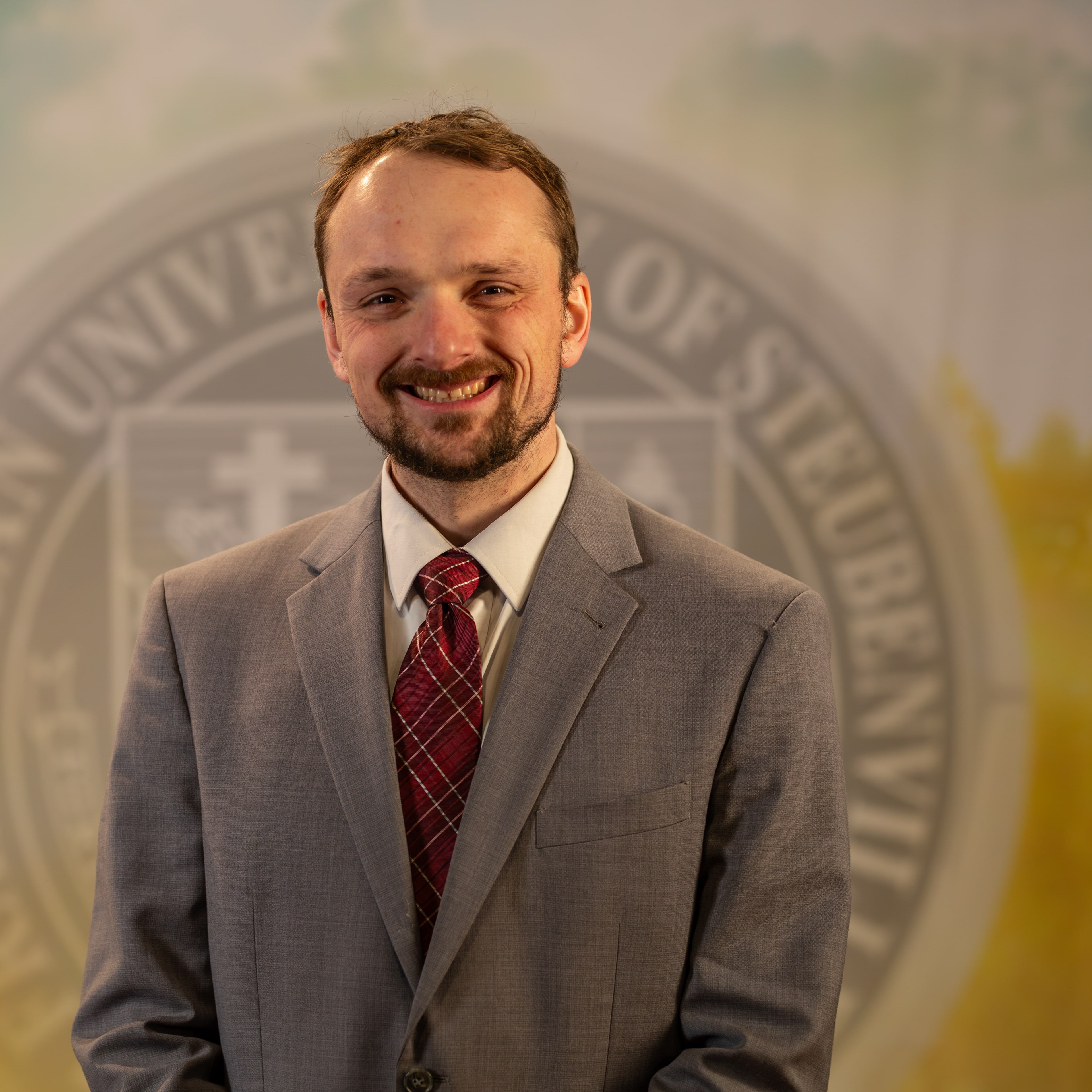 Dr. Tyler Brown standing in front of a university seal.