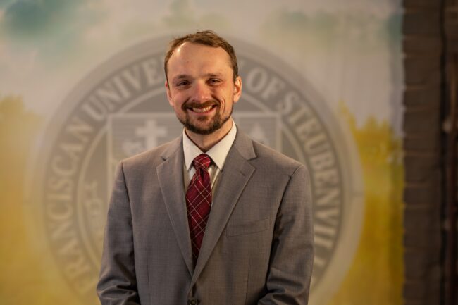 Dr. Tyler Brown standing in front of a university seal.